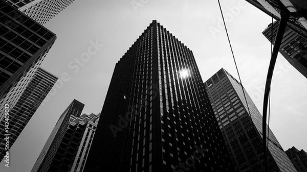 Obraz Widok z dołu na drapacze chmur, skrzyżowania i sygnalizację świetlną w czerni i bieli