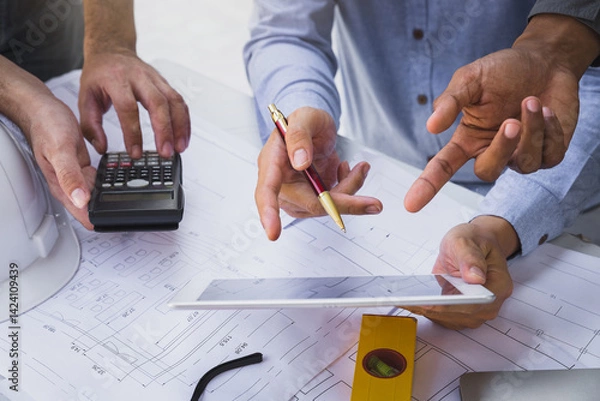 Obraz Engineers and architects pointing at digital tablet screens. Two Construction Engineers or Architects discussing at work with digital tablet, laptop and blueprint on construction site.