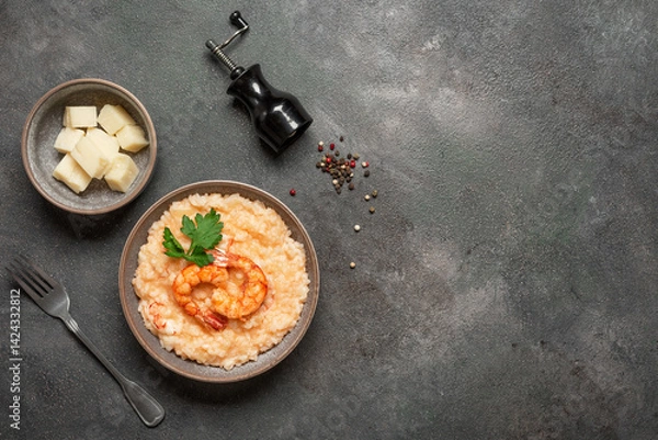 Fototapeta Bowl of risotto with shrimps on dark rustic background, top view, copy space