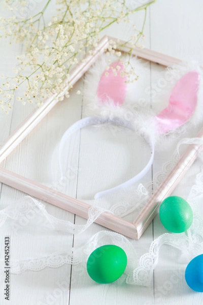 Obraz Easter bunny ears in a frame for pictures and colorful eggs on a white background. Selective color and space for text