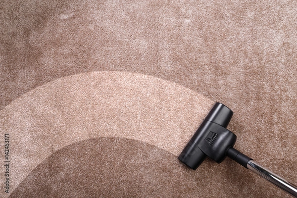 Fototapeta Vacuuming carpet with vacuum cleaner. Housework service. Close up of the head of a sweeper cleaning device.