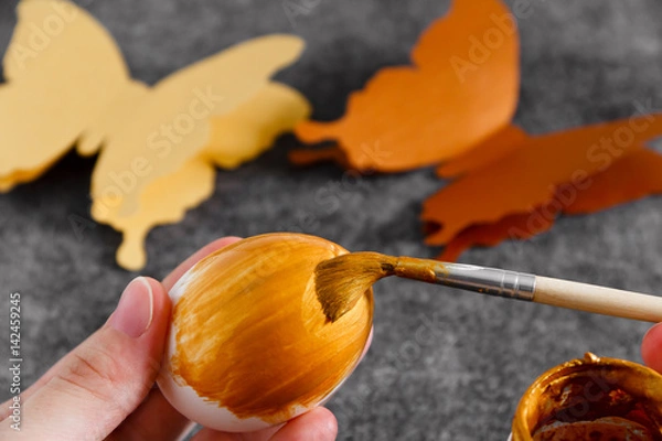 Obraz Workspace with easter decoration. Woman paints Easter eggs, slide view. Selective focus