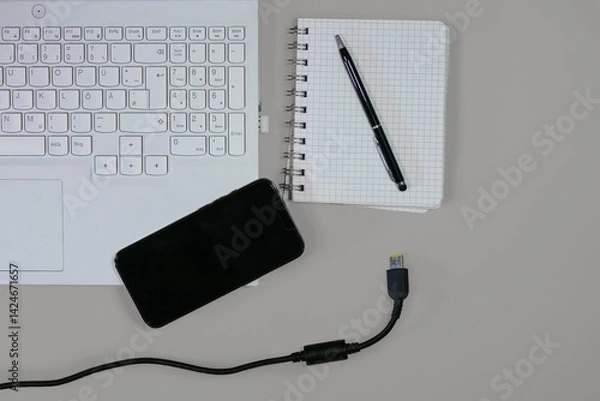 Fototapeta Flat lay on white background top view with copy space. Computer laptop keyboard, notebook, smartphone and cable. The concept of business, study or IT