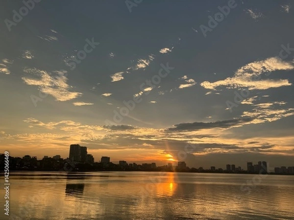 Fototapeta Golden Hour Reflections: Tranquil Waterfront Cityscape at Sunset with Perfect Mirror Effect on West Lake in Hanoi, Vietnam