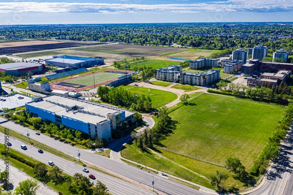 Fototapeta City view of a large empty lot with a green field