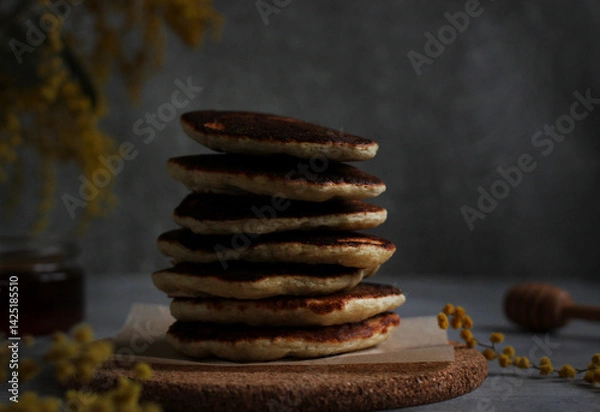 Fototapeta Pancakes in rows stacked close-up with honey and mimosa on a gray background
