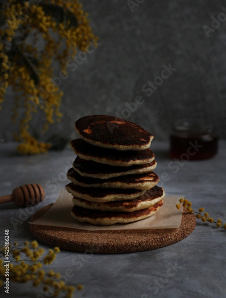 Fototapeta Pancakes in rows stacked close-up with honey and mimosa on a gray background