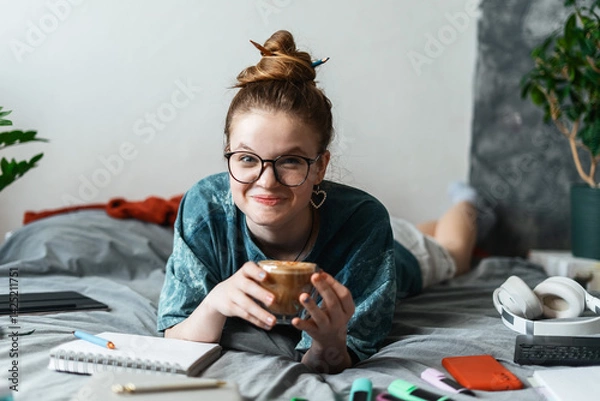 Fototapeta Teen girl organizing study materials while working on project. Educational supplies colorful markers, planner, and wireless keyboard, making home workspace functional and creative. Drinking coffee