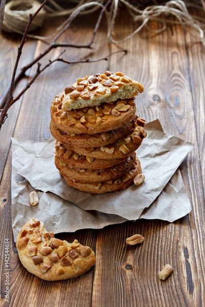Fototapeta Homemade cookies with a peanut on paper for pastries on wooden table. Selective focus.