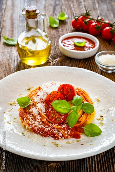 Obraz Spaghetti marinara - pasta with tomato sauce, parmesan cheese and basil leaves on wooden table	