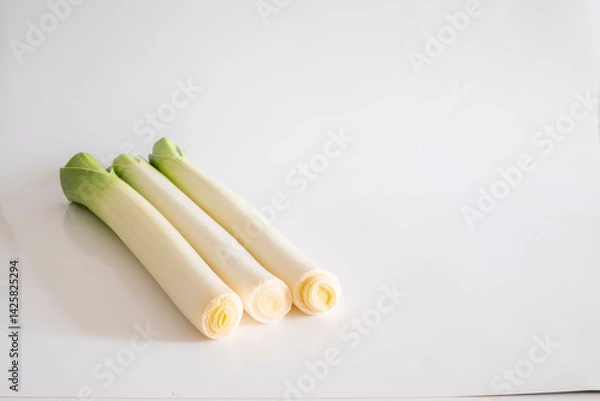 Fototapeta Three stalks of fresh green leek isolated on a white background with copy space. Allium ampeloprasum var. porrum, or spring onion, is one of the varieties of the Allium ampeloprasum species.