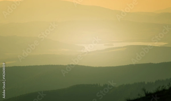 Fototapeta A beautiful, colorful, abstract mountain landscape with a hot summer haze in warm green tonality. Decorative, artistic look.