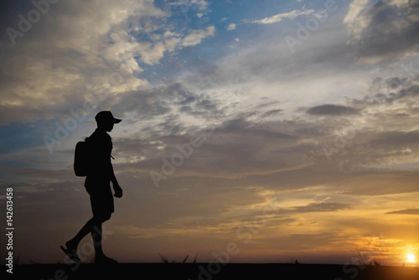 Fototapeta Silhouette of a man happy walking at sunset.