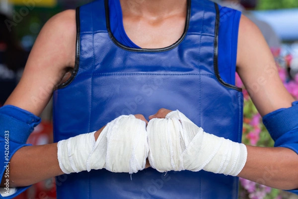 Fototapeta Boxing fighter wrapped fists blue gloves strength focus training combat athlete uniform resilience power challenge determination grit. Handwraps sportswear protection readiness brawler confidence.