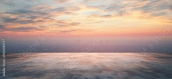 Fototapeta Cityscape view at sunset from a high vantage point, showcasing a vast urban sprawl under a colorful sky.  A concrete platform in the foreground offers a sense of place and scale