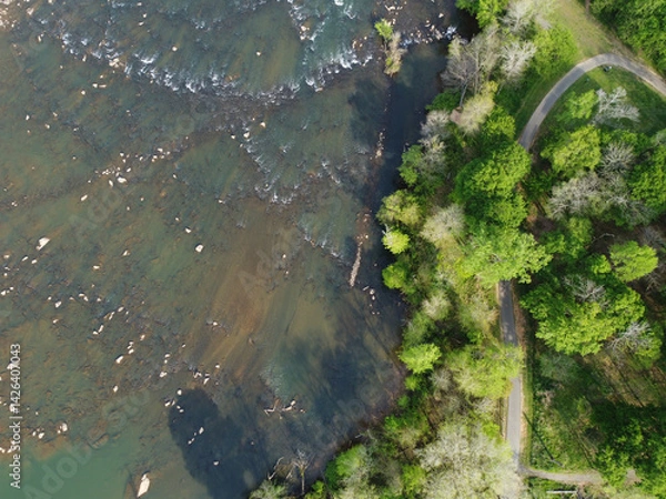 Fototapeta Catawba River meanders over rocks beside fitness path in Rock Hill, South Carolina
