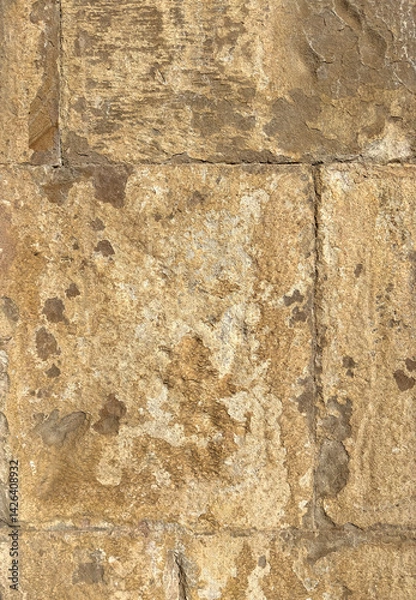 Fototapeta Beige sandstone church wall with large, textured bricks. Historic architecture detail, ideal as a natural stone background or rustic texture for design and creative projects.