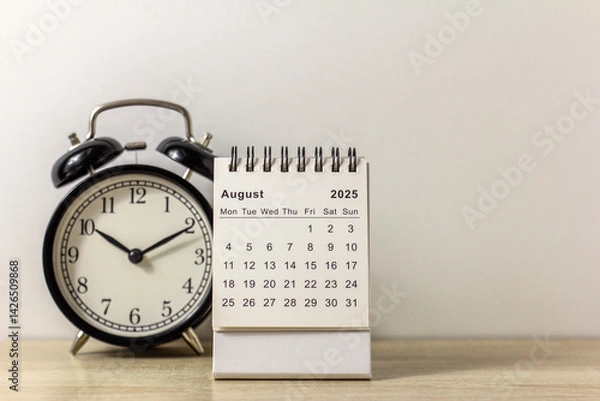 Fototapeta A desktop calendar for August 2025 and a clock on the table, where there is room to copy.