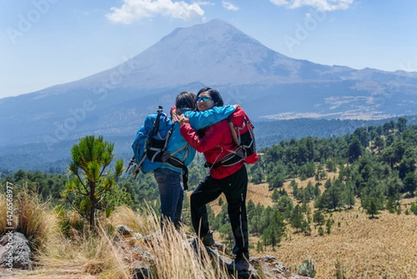 Obraz Hikers embracing on mountain top with iztaccíhuatl volcano in background