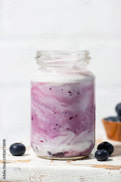 Obraz fruit yogurt with blueberries in a glass jar, vertical closeup
