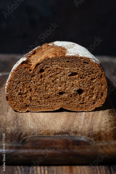 Obraz half rye bread on a wooden cutting board,closeup vertical