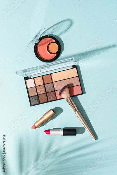 Obraz Make up products on blue background with shadows. Cosmetic palette, brushes and lipstick. Top view image.