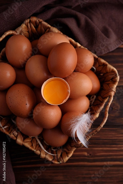 Fototapeta Basket of fresh farm chicken eggs with broken one on a wooden rustic background