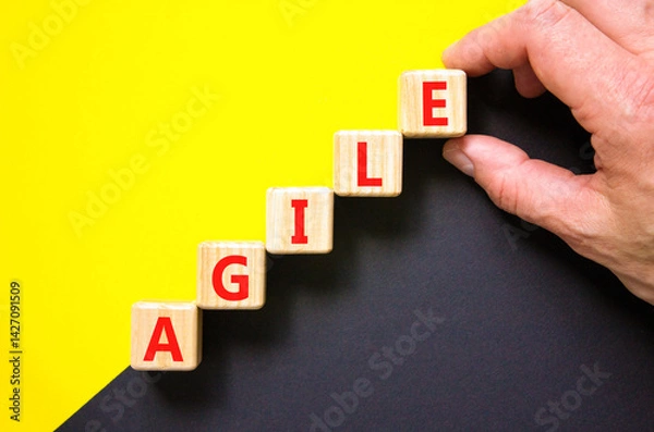 Fototapeta Agile symbol. Concept word Agile on beautiful wooden blocks. Beautiful yellow and black background. Businessman hand. Business agile concept. Copy space.