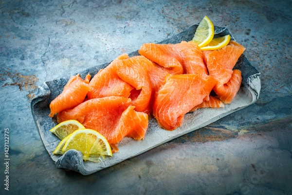 Fototapeta Traditional Norwegian smoked salmon in slices with lemon slices served as close-up on a Nordic design tray with text space