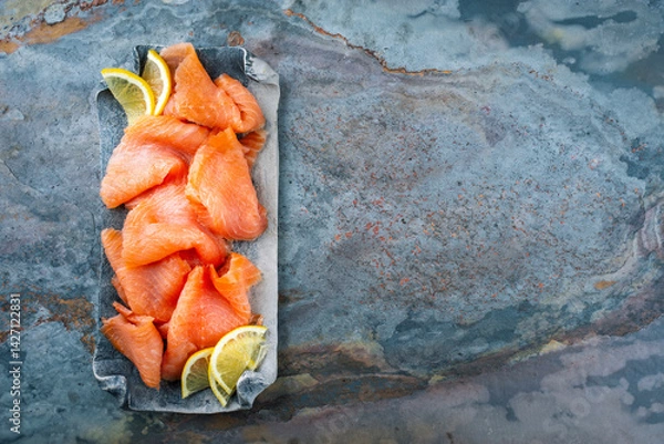 Fototapeta Traditional Norwegian smoked salmon in slices with lemon slices served as top view on a Nordic design tray