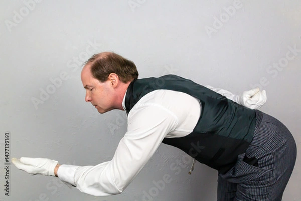 Fototapeta Butler in Formal Attire and White Gloves Bowing in Polite Greeting and Offering a Helping Hand. Professional Hospitality and Service.