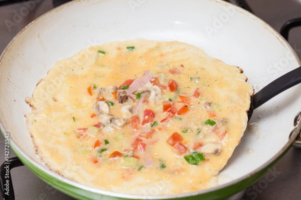 Fototapeta Omelet preparation : Flipping the omelet