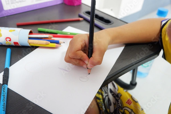 Fototapeta A boy's hand is practicing drawing shapes on paper.