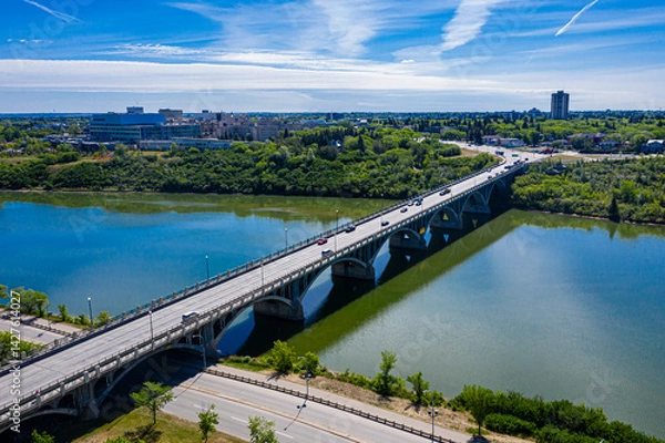 Fototapeta Bridge spans a river with a city in the background