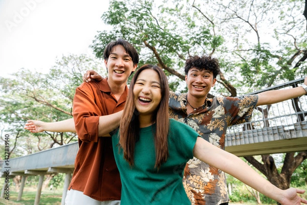 Obraz Joyful Friends Having Fun Outdoors in Park Embracing Each Other with Smiles Under Green Trees on a Sunny Day