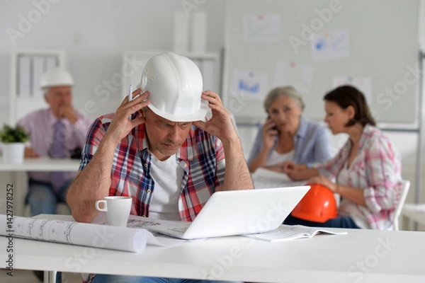 Fototapeta Stressed engineer at work on a project