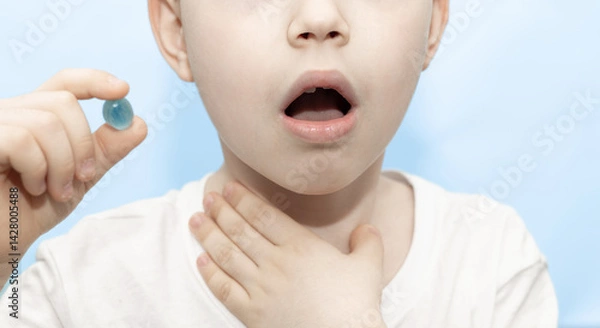 Obraz kid taking a pill, candy for sore throat. boy holding fist on mouth and coughing.isolated child putting pill on tongue. man hand holding many lozenges suck.