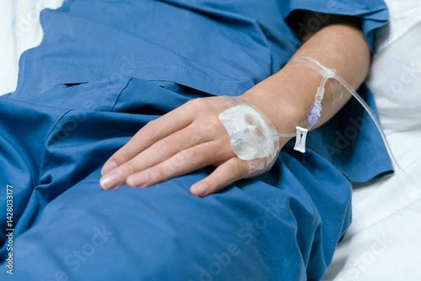 Obraz The saline tube on the left hand of the patient is giving the saline solution that lies in the hospital bed