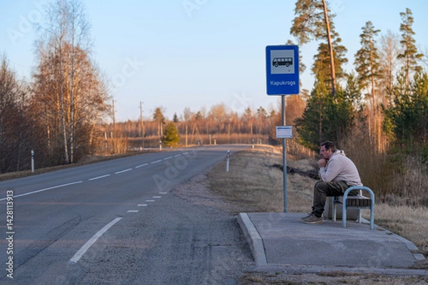 Obraz Waiting at a bus stop on a quiet road in early morning light