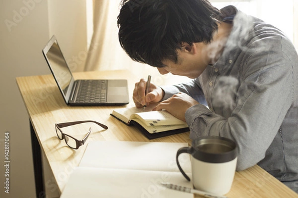 Obraz 机の上で仕事・勉強をする男性