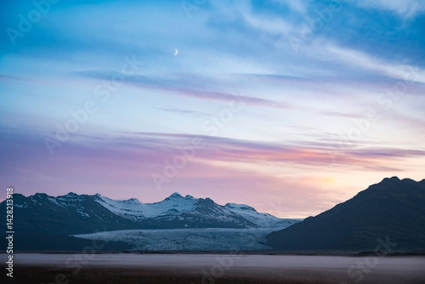 Obraz Twilight over Vatnajökull glacier in Iceland, with snow-covered peaks, pastel sky, rising crescent moon, and mist-covered plains evoking stillness and grandeur.