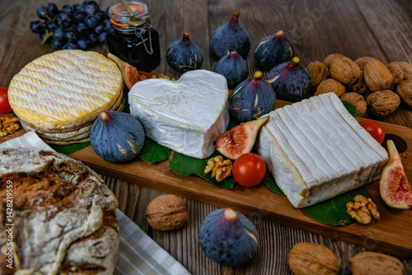 Obraz Selection of French cheeses from Normandy, AOP, Livarot, Neufchatel, Pont l'eveque, Rye bread, figs, walnuts, grapes, elderberry gelee. High quality photo