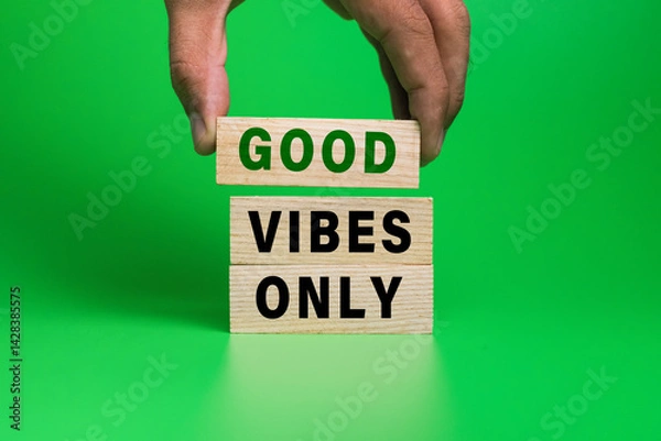 Fototapeta male hand put wooden blocks with good vibes only words isolated on green background