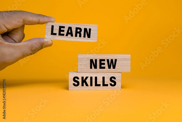 Fototapeta male hand put wooden blocks with learn new skills words text isolated on orange background