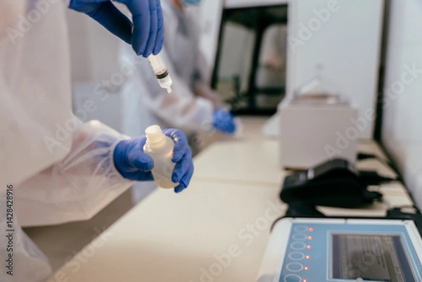 Obraz Close up of gloved hands filling syringe with breast milk for laboratory testing