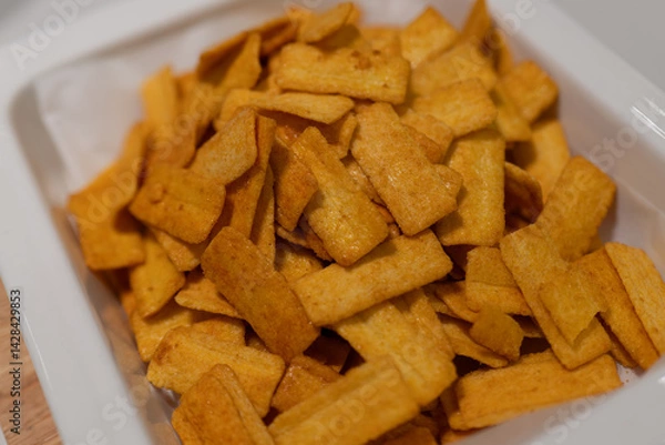 Obraz Golden Crispy Snacks in White Container, Perfect for Snacking