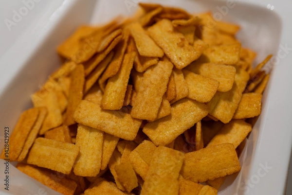 Obraz Golden Crispy Snacks in White Container, Perfect for Snacking