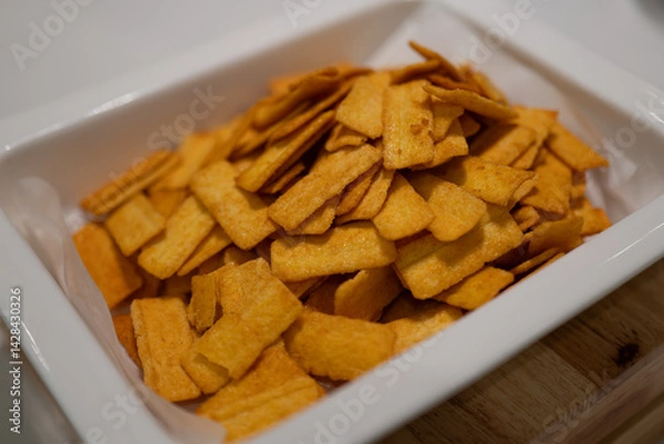 Obraz Golden Crispy Snacks in White Container, Perfect for Snacking