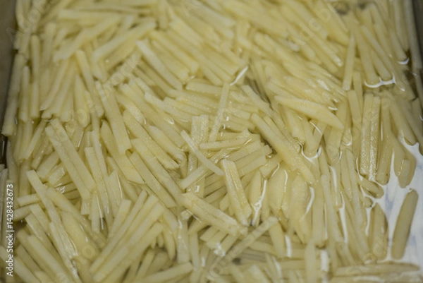 Obraz Freshly Shredded Potatoes Soaked in Water for Cooking Preparation