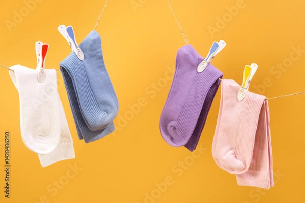 Fototapeta Colorful socks hanging on a line against a bright yellow background